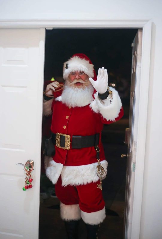 Santa Claus waving in an open doorway.