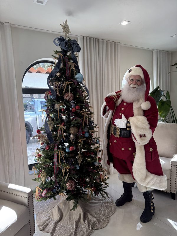 Santa Claus beside a decorated Christmas tree in a Miami home.