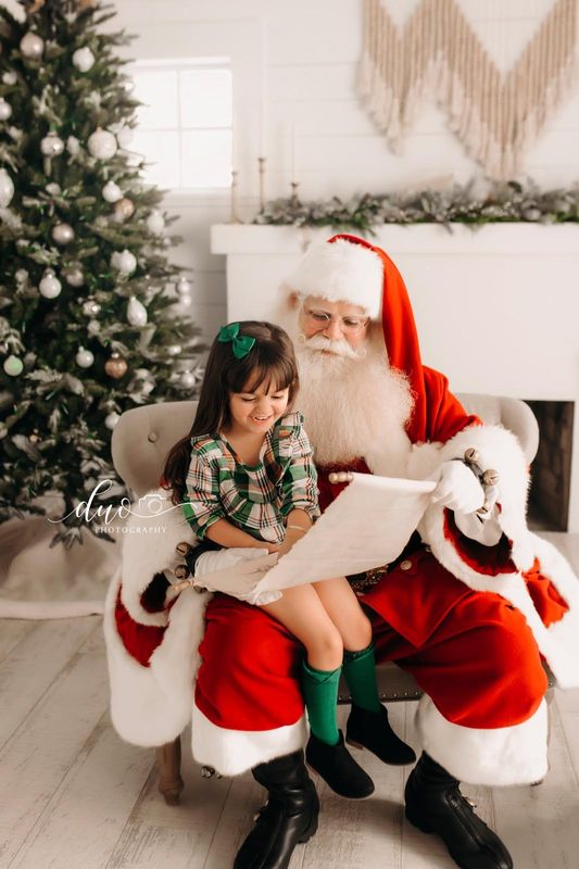 Santa Claus seated with a small child.