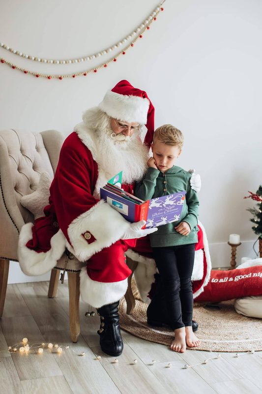 Santa Claus reading a book with a child.