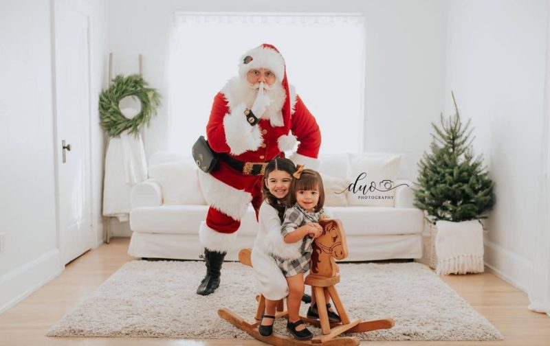 Santa Claus with children beside a rocking horse in a bright room.