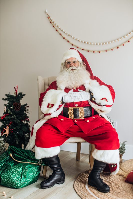 Santa Claus seated with his sack on a photograph set.